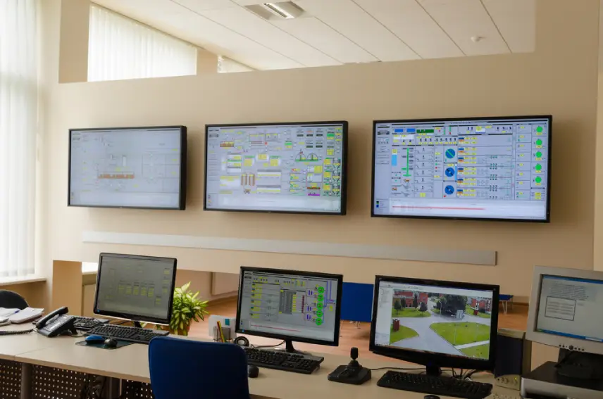 A room with four monitors and two computers.