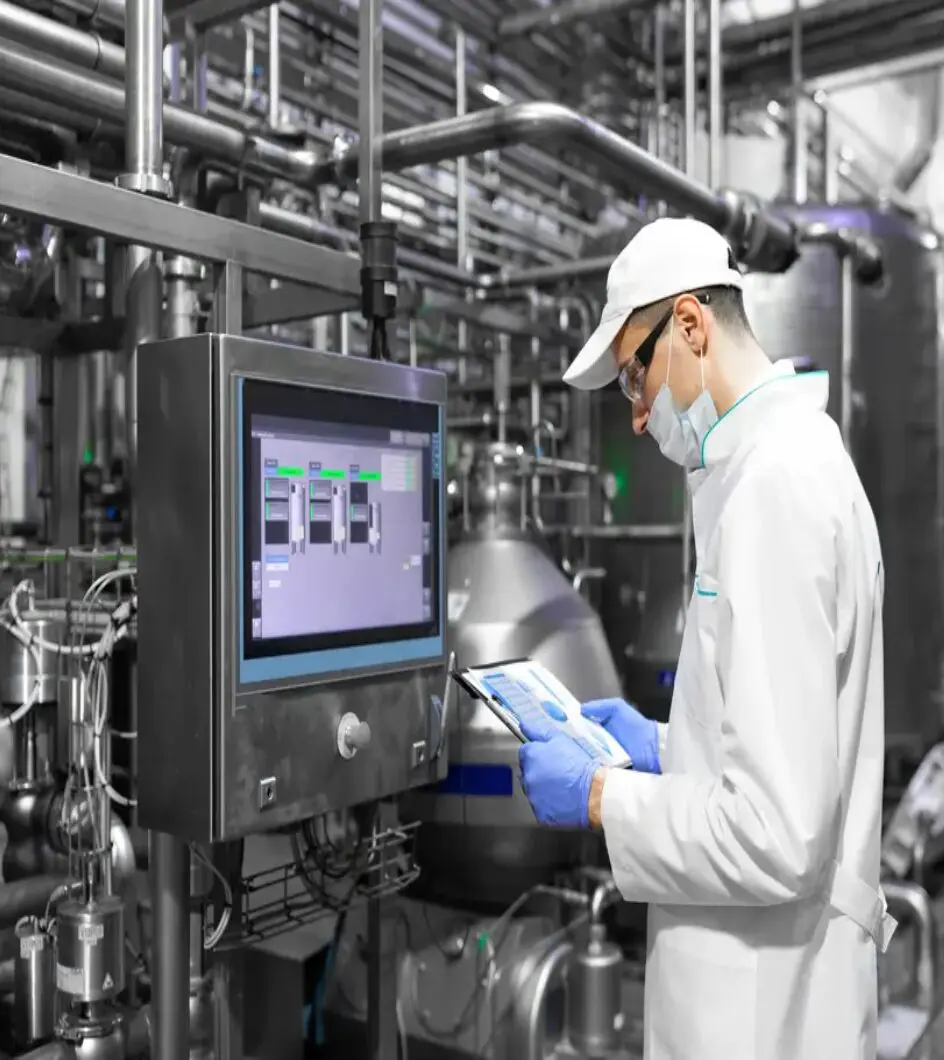 A man in white lab coat and hat looking at computer screen.